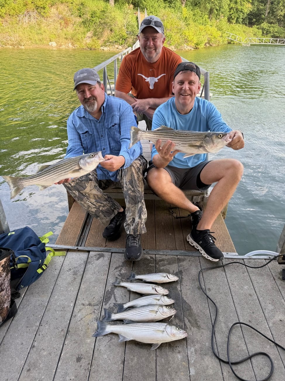 Two anglers holding striped bass